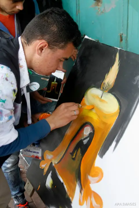 Palestinian youths paint a mural to mark the 22nd anniversary of the massacre of 29 Palestinian Muslim worshipers by Jewish extremist Baruch Goldstein at the Tomb of the Patriarchs on February 25, 1994 in the West Bank c...