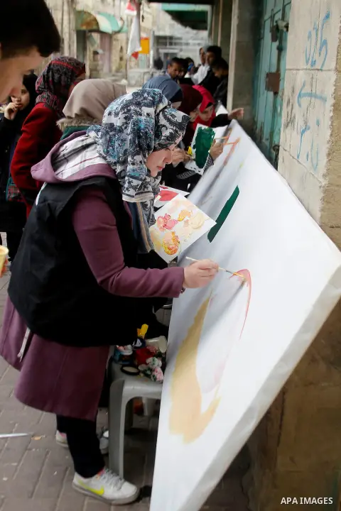 Palestinian youths paint a mural to mark the 22nd anniversary of the massacre of 29 Palestinian Muslim worshipers by Jewish extremist Baruch Goldstein at the Tomb of the Patriarchs on February 25, 1994 in the West Bank c...