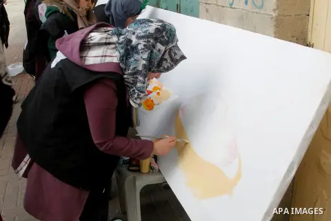 Palestinian youths paint a mural to mark the 22nd anniversary of the massacre of 29 Palestinian Muslim worshipers by Jewish extremist Baruch Goldstein at the Tomb of the Patriarchs on February 25, 1994 in the West Bank c...