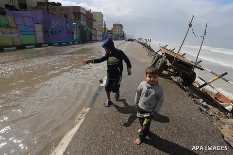 Palestinian boys play on a rainy day at Shati refugee camp in Gaza city, on February 22, 2016. Photo by Mohammed Asad