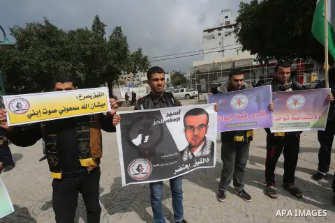 Palestinians hold posters bearing a portrait of Palestinian journalist Mohammed al-Qiq who is imprisoned in an Israeli jail during a protest in support of his hunger strike in Gaza city on Feb. 23, 2016. Photo by Mohamme...