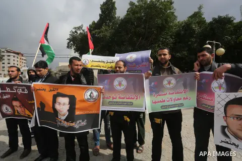 Palestinians hold posters bearing a portrait of Palestinian journalist Mohammed al-Qiq who is imprisoned in an Israeli jail during a protest in support of his hunger strike in Gaza city on Feb. 23, 2016. Photo by Mohamme...