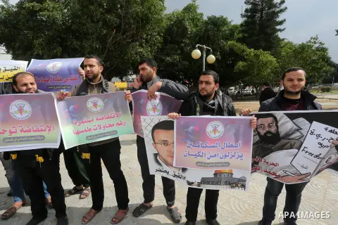 Palestinians hold posters bearing a portrait of Palestinian journalist Mohammed al-Qiq who is imprisoned in an Israeli jail during a protest in support of his hunger strike in Gaza city on Feb. 23, 2016. Photo by Mohamme...