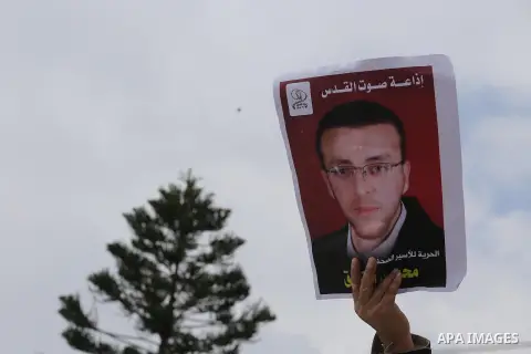 Palestinians hold posters bearing a portrait of Palestinian journalist Mohammed al-Qiq who is imprisoned in an Israeli jail during a protest in support of his hunger strike in Gaza city on Feb. 23, 2016. Photo by Mohamme...