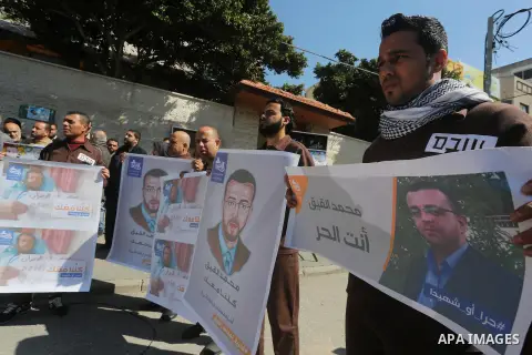 Palestinian journalists hold posters bearing a portrait of Palestinian journalist Mohammed al-Qiq who is imprisoned in an Israeli jail during a protest in support of his hunger strike in front of Red Cross office, in Gaz...
