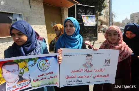 Palestinian journalists hold posters bearing a portrait of Palestinian journalist Mohammed al-Qiq who is imprisoned in an Israeli jail during a protest in support of his hunger strike in front of Red Cross office, in Gaz...