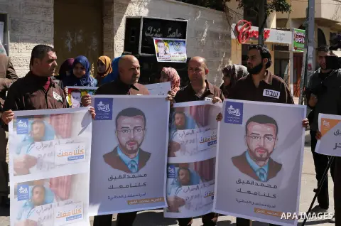 Palestinian journalists hold posters bearing a portrait of Palestinian journalist Mohammed al-Qiq who is imprisoned in an Israeli jail during a protest in support of his hunger strike in front of Red Cross office, in Gaz...