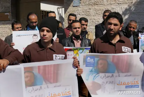 Palestinian journalists hold posters bearing a portrait of Palestinian journalist Mohammed al-Qiq who is imprisoned in an Israeli jail during a protest in support of his hunger strike in front of Red Cross office, in Gaz...