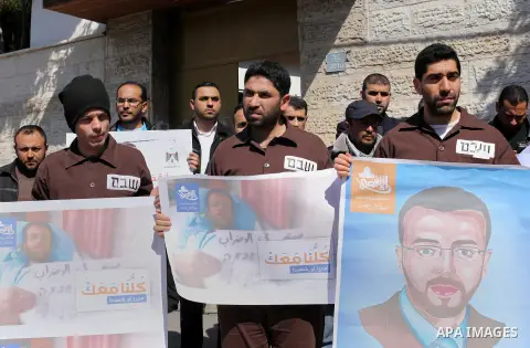 Palestinian journalists hold posters bearing a portrait of Palestinian journalist Mohammed al-Qiq who is imprisoned in an Israeli jail during a protest in support of his hunger strike in front of Red Cross office, in Gaz...