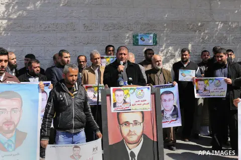 Palestinian journalists hold posters bearing a portrait of Palestinian journalist Mohammed al-Qiq who is imprisoned in an Israeli jail during a protest in support of his hunger strike in front of Red Cross office, in Gaz...