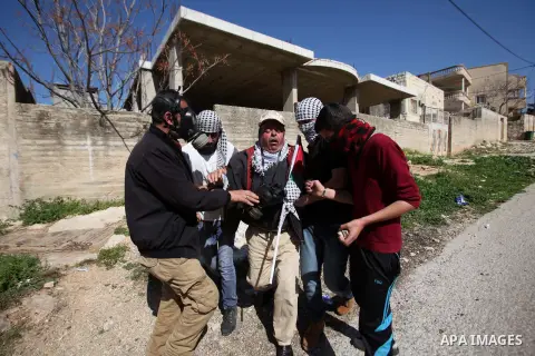 Palestinians help a wounded protester during clashes with Israeli security forces following a protest against the expropriation of Palestinian land by Israel in the West Bank village of Kafr Qaddum, near the northern cit...