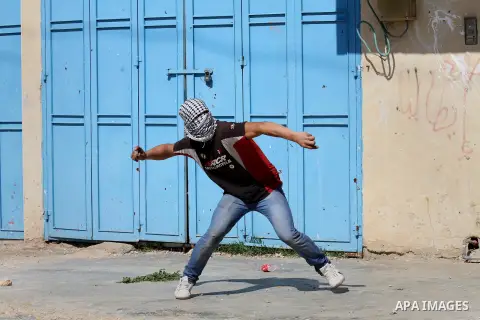 A Palestinian protester throws stones toward Israeli security forces during clashes following a protest against the expropriation of Palestinian land by Israel in the West Bank village of Kafr Qaddum, near the northern c...