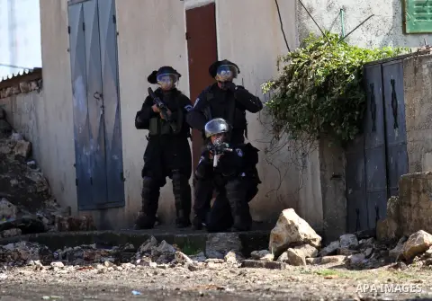 A member of Israeli security forces aims his weapon at Palestinian protesters during clashes following a protest against the expropriation of Palestinian land by Israel in the West Bank village of Kafr Qaddum, near the n...
