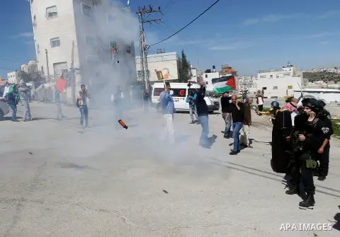 Palestinian protesters run for cover from as Israeli troops fire sound and tear gas grenades during a demonstration against the closure of Shuhada street to Palestinians, on the 22nd anniversary of the closure, in the We...