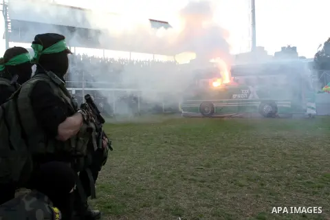 Palestinian militants of the Ezzedine al-Qassam Brigades, the armed wing of the Hamas movement, look at a mock bus burning during a show as part of an anti-Israel rally on February 26, 2016, in the southern Gaza Strip to...
