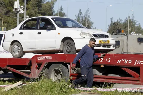 An Israeli policeman stands guard during the removal of a car used by a Palestinian woman who, the Israeli military said, rammed it into an Israeli soldier before she was shot dead by the Israeli troops, at a main juncti...