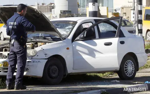 Israeli security forces inspect a car used by a Palestinian woman who, the Israeli military said, rammed it into an Israeli soldier before she was shot dead by the Israeli troops, at a main junction near the Israeli sett...
