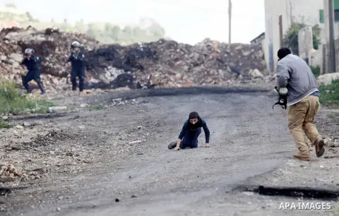 A Palestinian man rushes towards a boy who was injured during clashes with Israeli security forces following a demonstration against the expropriation of Palestinian land by Israel, in the village of Kfar Qaddum, near Na...
