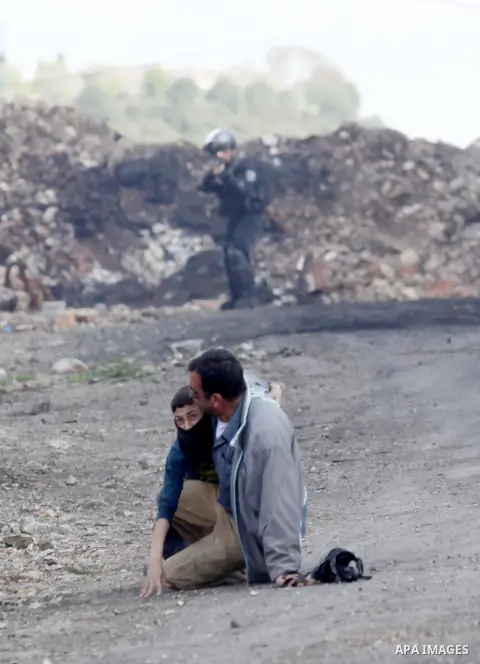A Palestinian man carries a boy after he was injured during clashes with Israeli security forces following a demonstration against the expropriation of Palestinian land by Israel, in the village of Kfar Qaddum, near Nabl...