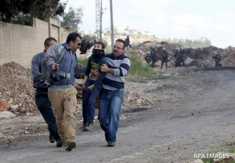 A Palestinian man carries a boy after he was injured during clashes with Israeli security forces following a demonstration against the expropriation of Palestinian land by Israel, in the village of Kfar Qaddum, near Nabl...