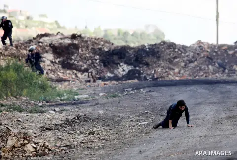 A Palestinian man rushes towards a boy who was injured during clashes with Israeli security forces following a demonstration against the expropriation of Palestinian land by Israel, in the village of Kfar Qaddum, near Na...