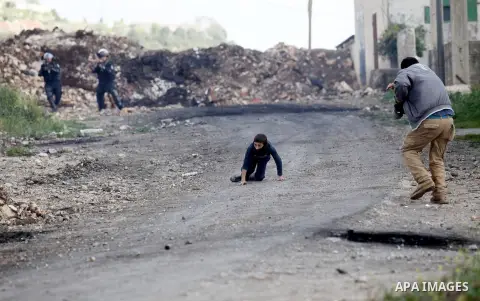 A Palestinian man rushes towards a boy who was injured during clashes with Israeli security forces following a demonstration against the expropriation of Palestinian land by Israel, in the village of Kfar Qaddum, near Na...