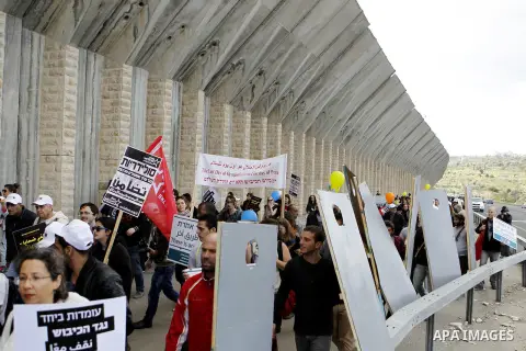 Peace activists hold placards during a joint Israeli-Palestinian peace march along the Israeli controvertial separation wall in the West Bank city of Beit Jala between Bethlehem and Jerusalem, on March 4, 2016. Peace act...