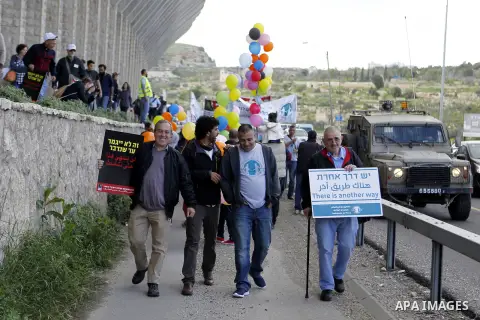 Peace activists hold placards during a joint Israeli-Palestinian peace march along the Israeli controvertial separation wall in the West Bank city of Beit Jala between Bethlehem and Jerusalem, on March 4, 2016. Peace act...
