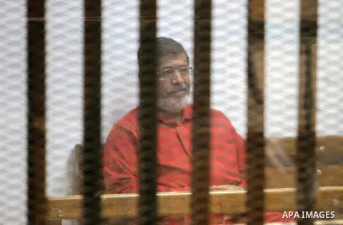 Ousted Egyptian president Mohammed Morsi sits behind bars during his trail as part of the so-called 'Qatar espionage' case, in a court in Cairo on March 06, 2016. The defendants are accused of 'leaking important national...