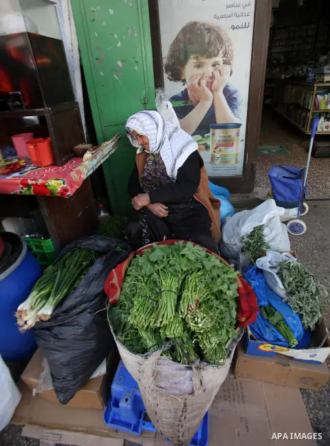 A Palestinian woman sells vegetables at a market, in the West Bank city of Nablus, on March 8, 2016. People around the globe celebrate International Women's Day, which dates back to the beginning of the 20th Century and...