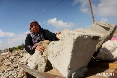 Palestinian woman Jihan Abu Muhsen collects bricks for sale with her son Mohammad from the ruins of a house destroyed during the 2014 war in Khan Younis in the southern Gaza Strip March 17, 2016. Abu Muhsen gathers brick...
