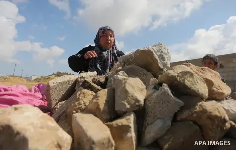 Palestinian woman Jihan Abu Muhsen collects bricks for sale with her son Mohammad from the ruins of a house destroyed during the 2014 war in Khan Younis in the southern Gaza Strip March 17, 2016. Abu Muhsen gathers brick...