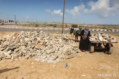 Palestinian woman Jihan Abu Muhsen collects bricks for sale with her son Mohammad from the ruins of a house destroyed during the 2014 war in Khan Younis in the southern Gaza Strip March 17, 2016. Abu Muhsen gathers brick...