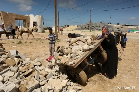 Palestinian woman Jihan Abu Muhsen collects bricks for sale with her son Mohammad from the ruins of a house destroyed during the 2014 war in Khan Younis in the southern Gaza Strip March 17, 2016. Abu Muhsen gathers brick...