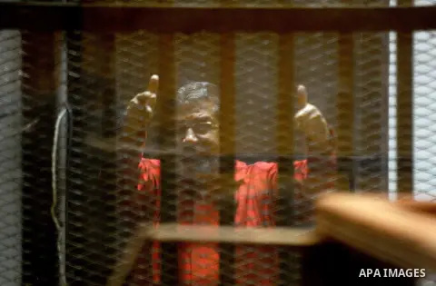 Ousted Egyptian president Mohammed Morsi sits behind bars during his trail as part of the so-called 'Qatar espionage' case, in a court in Cairo on March 21, 2016. The defendants are accused of 'leaking important national...