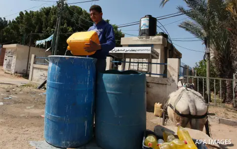 Palestinian children fill plastic bottles and jerry cans with drinking water from a public tap marking the Water World Day in Beit Lahia in the northern Gaza Strip, on March 22, 2016. Photo by Ashraf Amra