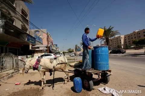 Palestinian children fill plastic bottles and jerry cans with drinking water from a public tap marking the Water World Day in Beit Lahia in the northern Gaza Strip, on March 22, 2016. Photo by Ashraf Amra