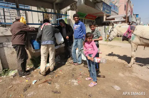 Palestinian children fill plastic bottles and jerry cans with drinking water from a public tap marking the Water World Day in Beit Lahia in the northern Gaza Strip, on March 22, 2016. Photo by Ashraf Amra