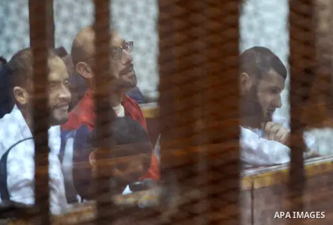 Defendants of Egyptian Muslim Brotherhood sit behind bars during the 'Qatar espionage' case, along with ousted Islamist president Mohamed Morsi (unseen) in a court in Cairo on March 23, 2016. The defendants are accused o...