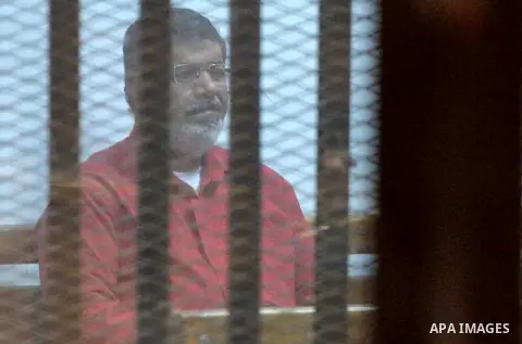 Ousted Egyptian president Mohammed Morsi sits behind bars during his trail as part of the so-called 'Qatar espionage' case, in a court in Cairo on March 23, 2016. The defendants are accused of 'leaking important national...