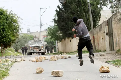 A Palestinian protester hurls stones toward An Israeli truck sprays foul smelling water during clashes with Israeli security forces following a demonstration against the expropriation of Palestinian land by Israel in the...