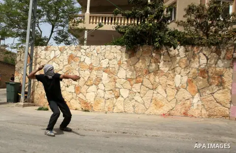 A Palestinian protester uses a slingshot to hurl stones toward Israeli security forces during clashes following a demonstration against the expropriation of Palestinian land by Israel in the village of Kfar Qaddum, near...