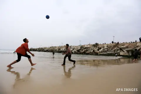 Palestinian children play volleyball at the beach of the Mediterranean sea on the coast of Gaza city, on March 25, 2016. Photo by Yasser Qudih