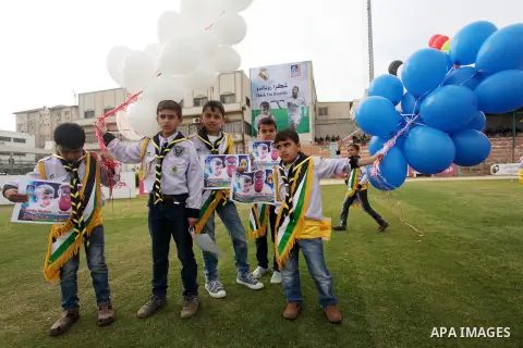 Palestinian chlidren hold ballons and posters bearing a portrait of Palestinian boy Ahmed Dawabsha, 5, who suffered severe burns in an arson attack by suspected Jewish attackers on his family home last July and in which...