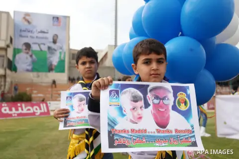 Palestinian chlidren hold ballons and posters bearing a portrait of Palestinian boy Ahmed Dawabsha, 5, who suffered severe burns in an arson attack by suspected Jewish attackers on his family home last July and in which...