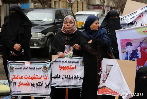 Palestinian families of martyrs, hold banners during a protest to demand their salaries, in front of Red cross office, in Gaza city, on March 28, 2016. Photo by Mohammed Asad