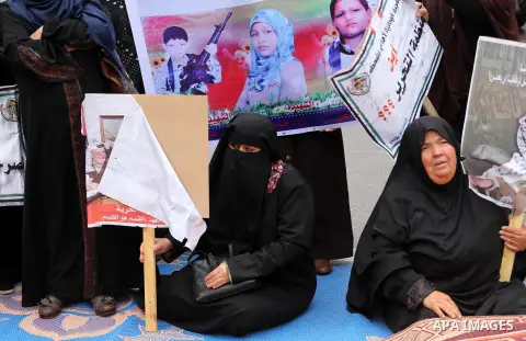 Palestinian families of martyrs, hold banners during a protest to demand their salaries, in front of Red cross office, in Gaza city, on March 28, 2016. Photo by Mohammed Asad