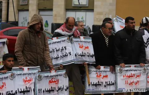 Palestinian families of martyrs, hold banners during a protest to demand their salaries, in front of Red cross office, in Gaza city, on March 28, 2016. Photo by Mohammed Asad
