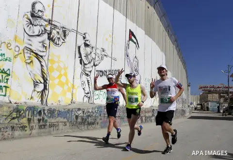 A participant runs past the controversial Israeli barrier during the annual Right to Movement Palestine Marathon in the West Bank town of Bethlehem April 1, 2016. Photo by Wisam Hashlamoun
