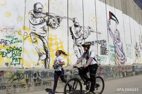 A participant runs past the controversial Israeli barrier during the annual Right to Movement Palestine Marathon in the West Bank town of Bethlehem April 1, 2016. Photo by Wisam Hashlamoun